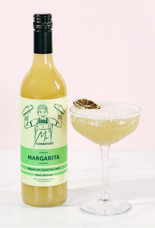 Bottle of Mr. Consistent Margarita Mix next to a margarita mockatil in a coupe glass garnished with dried lime