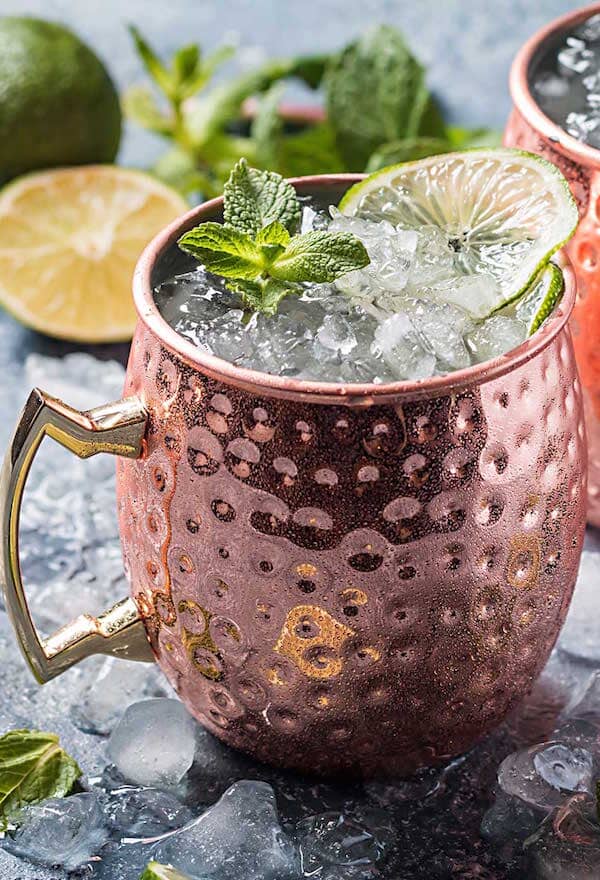 Moscow Mule Mocktail into a copper mug and garnished with fresh lime wheels and mint leaves