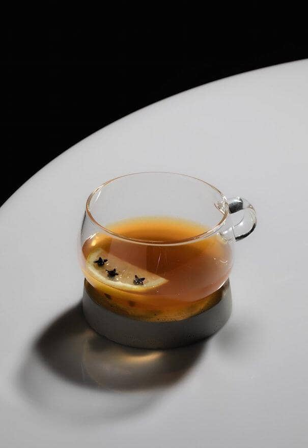 Rum mocktail in a glass mug garnished with clove a studded lemon slice 