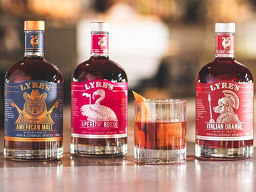 Boulevardier Whiskey Mocktail next to bottles of Lyre's American Malt, Lyre's Aperitif Rosso and Lyre's Italian Orange