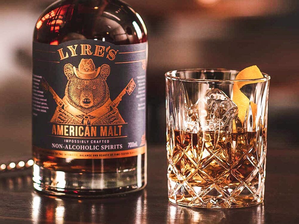 Bottle of Lyre's American Malt next to an old fashioned whiskey mocktail