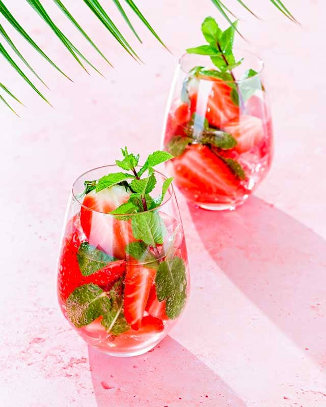 Two glasses of Strawberry Mojito Mocktail garnished with strawberries and mint leaves
