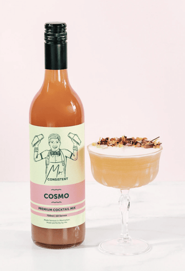 Bottle of Mr. Consistent Cosmopolitan Cocktail Mix next to a cosmopolitan mocktail garnished with edible flowers Sans Drinks