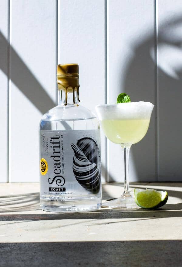 Fizz gin mocktail garnished with mint leaves next to a bottle of Seadrift Coastal  Sans Drinks