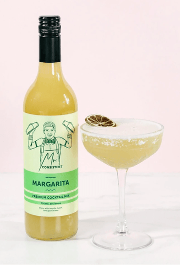 Bottle of Mr. Consistent Margarita Mix next to a margarita mockatil in a coupe glass garnished with dried lime Sans Drinks