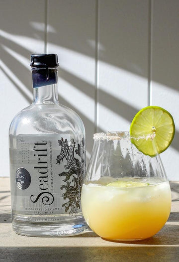 Salty Dog Mocktail garnished with a lime wheel next to a bottle of Seadrift Classic