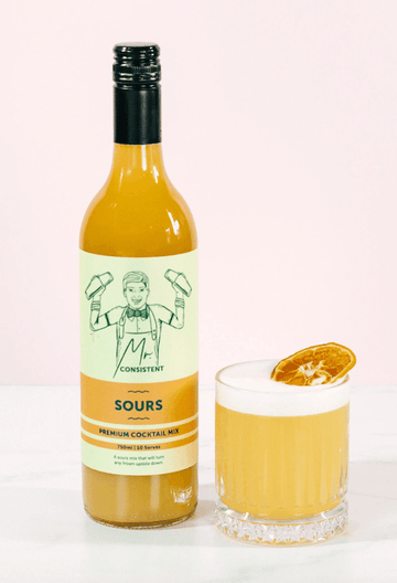 Bottle of Mr Consistent Sours mix next to a glass of whiskey sour mocktail