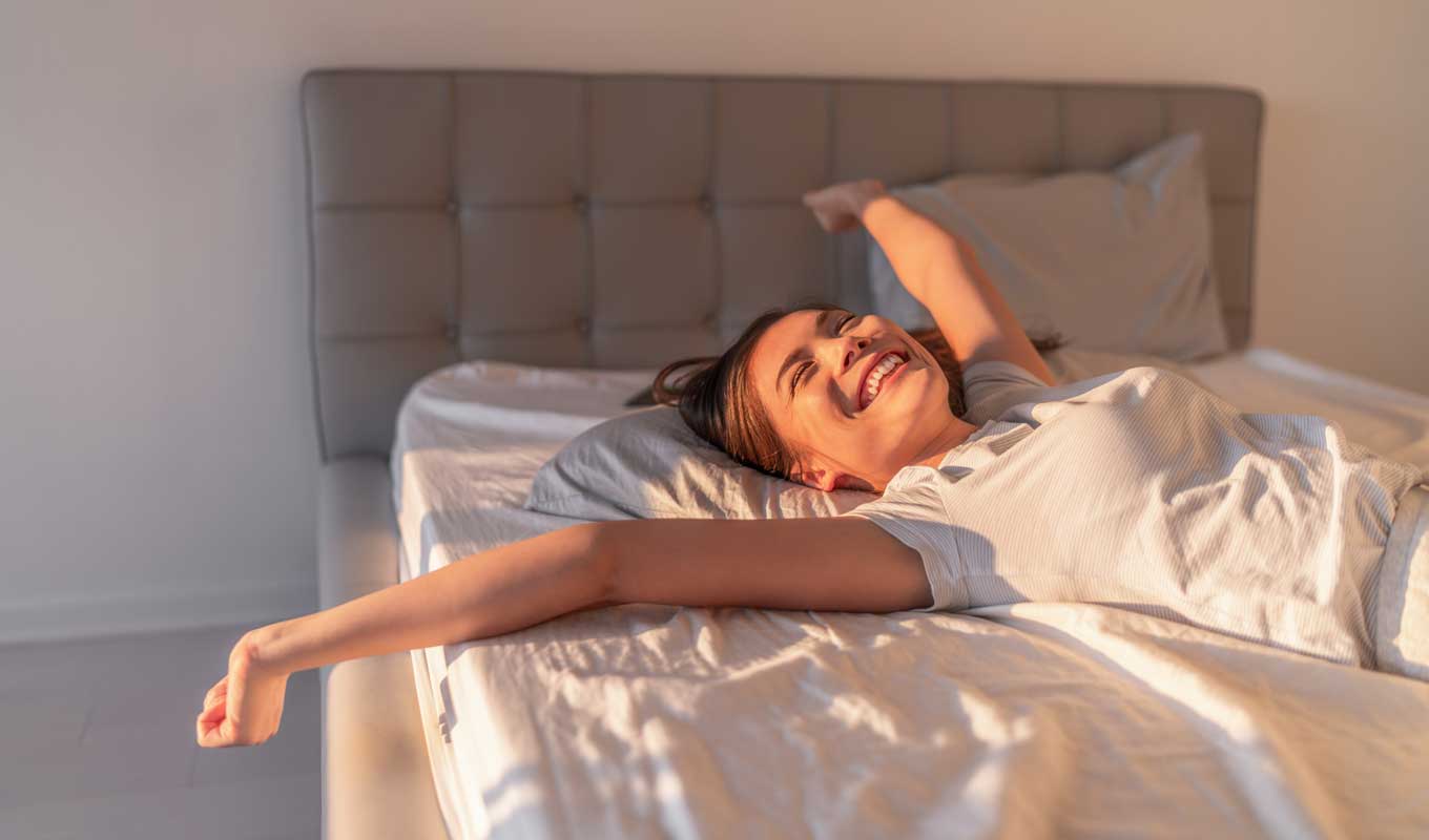 Happy woman stretching in bed
