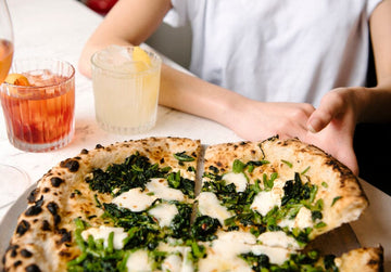 Reaching out for a slice of pizza with non-alcoholic cocktails on the side Sans Drinks