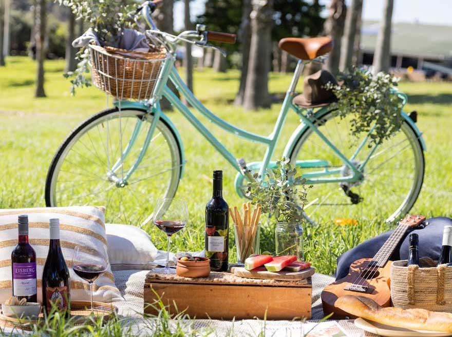 A picnic set up with three bottles of non-alcoholic wine and a bike  Sans Drinks