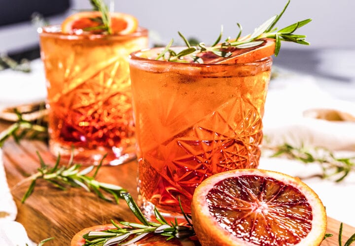 Two glasses of Blood Orange Spritz garnished with blood orange and sprig of rosemary