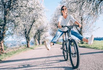 A happy woman rinding a bike Sans Drinks