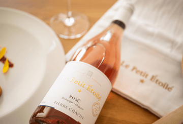 A bottle of Le Petit Etoile Rosé laid flat on a dinner table
