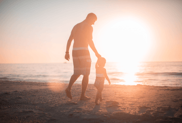 Father and son holding hands at the beach Sans Drinks