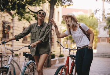 Two happy women riding bikes Sans Drinks