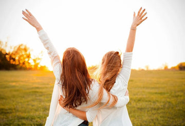 Two women hugging each other with their arms up in the air