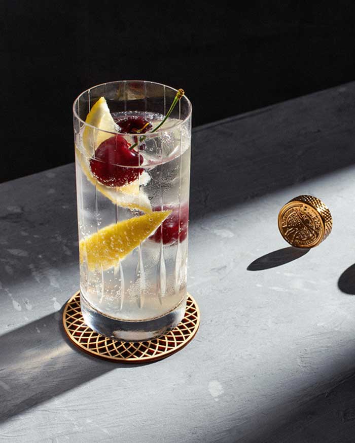 Non-Alcoholic Tom Collins Cocktail in a highball glass with lemon and Cherries