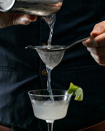 Bartender straining rum mocktail into a glass