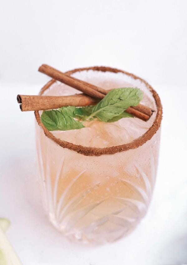 Rose champagne mocktail in a cinnamon rimmed glass and garnished with cinnamon sticks
