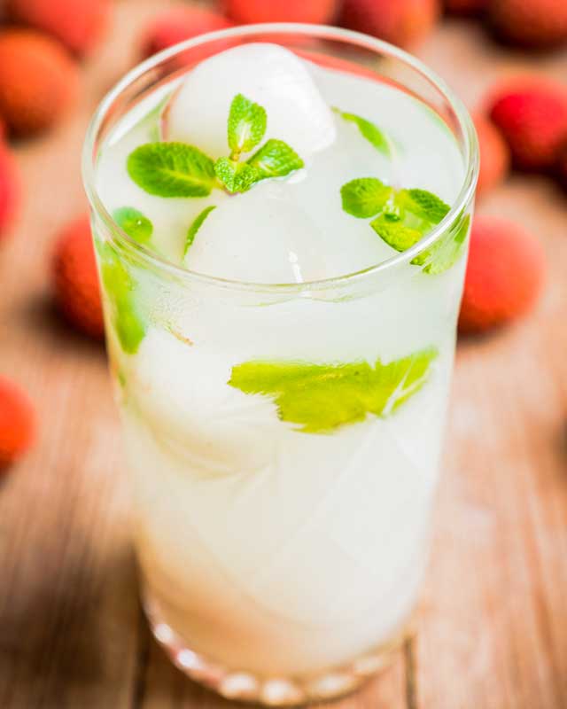 Lychee Mojito Mocktail garnished with mint leaves and lychees Sans Drinks