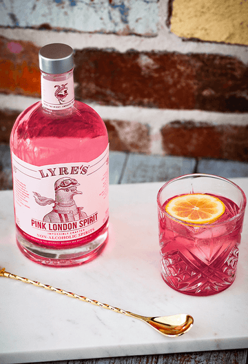 Bottle of Lyre's Pink London Spirit next to a pink negroni mocktail