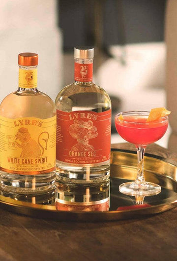 Cosmopolitan Mocktail next to a bottle of Lyre's White Cane Spirit and a bottle of Lyre's Orange Sec