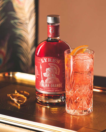 Italian orange mocktail next to a bottle of Lyre's italian orange Sans Drinks