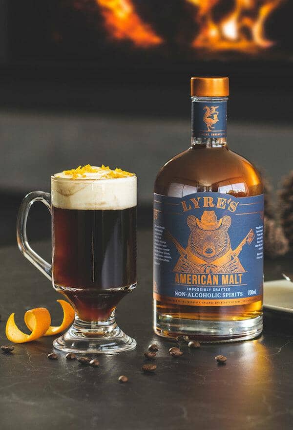 Bottle of Lyre's American Malt next to a glass of maple coffee mocktail