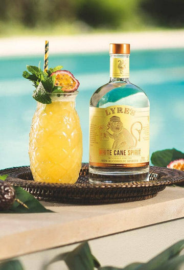 Passionfruit Pina Colada Mocktail garnished with passionfruit and mint leaves next to a bottle of Lyre's White Cane Spirit