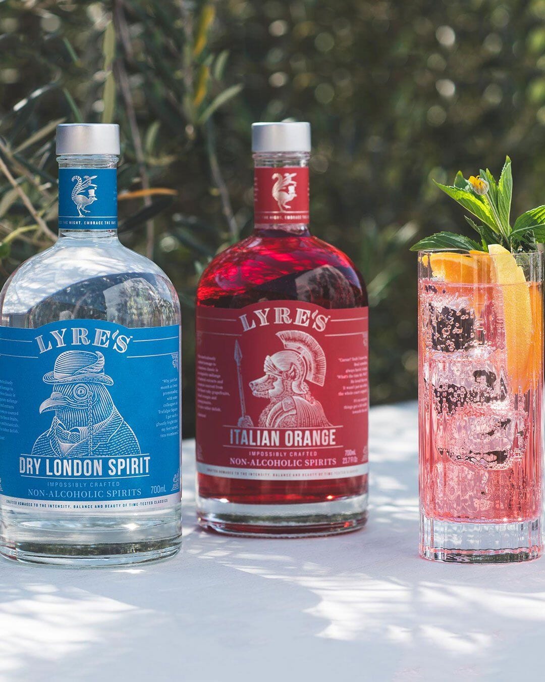 Bottle of Lyre’s Dry London Spirit and a bottle of Lyre’s Italian Orange next to a glass of gin fizz mocktail
