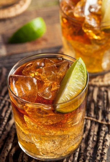 Dark & Stormy Rum Mocktail garnished with a lime wedge in a glass filled with ice