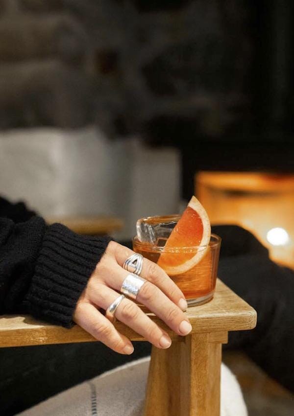 Female hand holding a glass of Americano Mocktail garnished with a grapefruit wedge