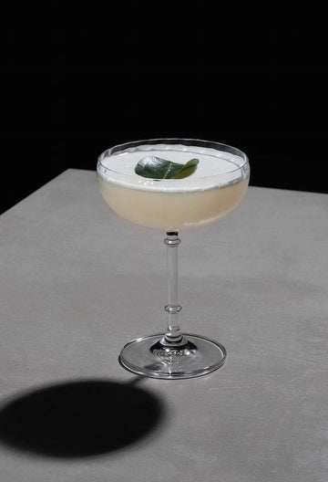 Lemon and Lime Sour Mocktail in a coupe glass garnished with a kaffir lime leaf