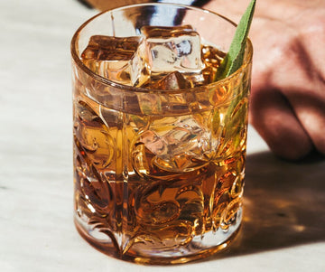 Bottle of Abstinence Epilogue X next to a stormy whiskey mocktail garnished with a lime wedge in a glass filled with ice Sans Drinks