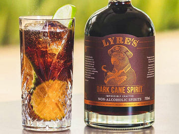 Cuba Libre Rum Mocktail garnished with lime wheels next to a bottle of Lyre's Dark Cane Spirit