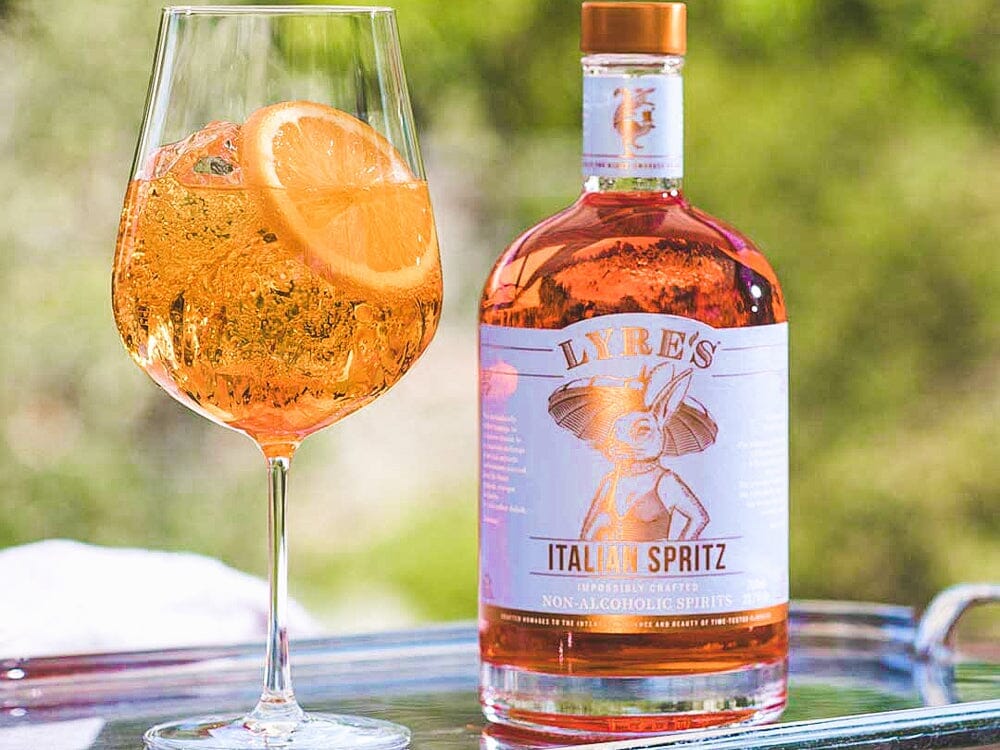 Amalfi Spritz Mocktail garnished with orange next to a bottle of Lyre's Italian Spritz