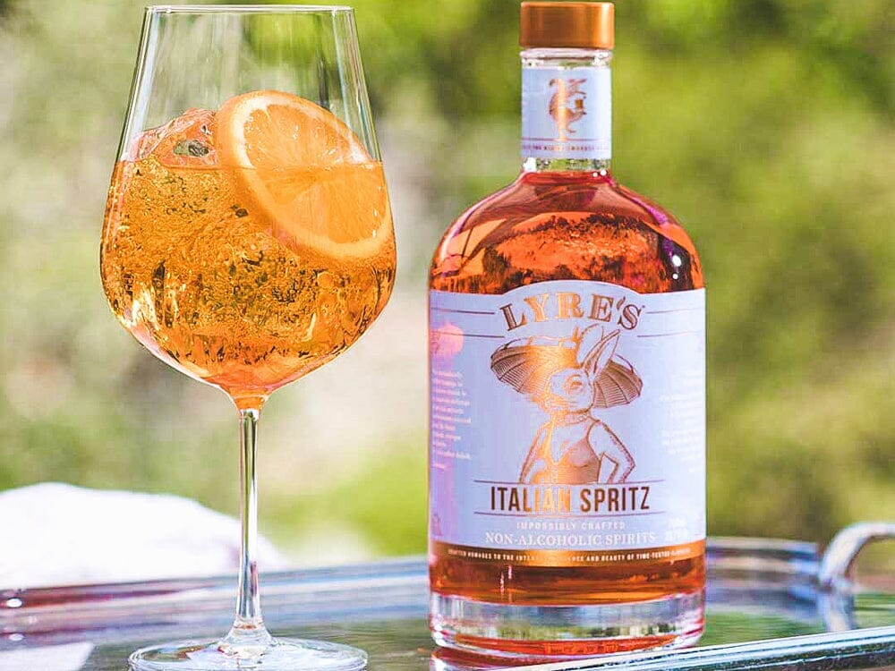 Amalfi Spritz Mocktail garnished with orange next to a bottle of Lyre's Italian Spritz Sans Drinks