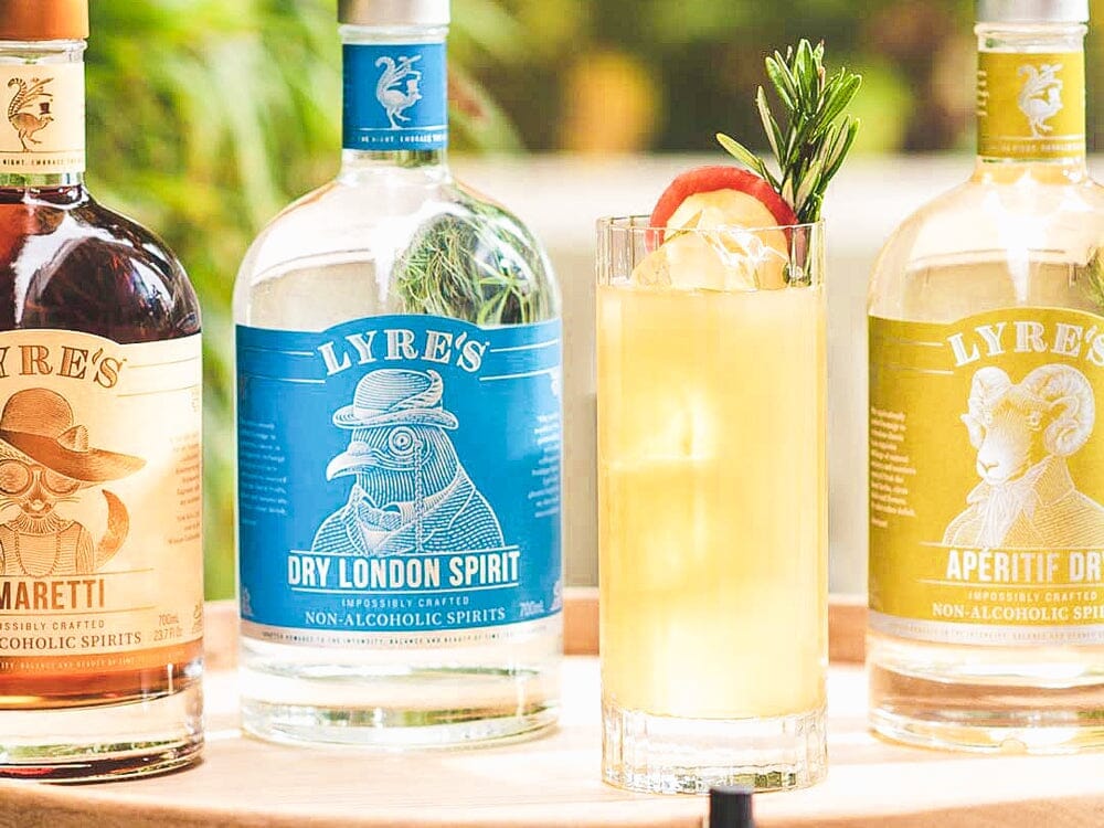 Fizz gin mocktail next to bottles of Lyre's Dry London Spirit, Lyre's Amaretti and Lyre's Aperitif Dry Sans Drinks