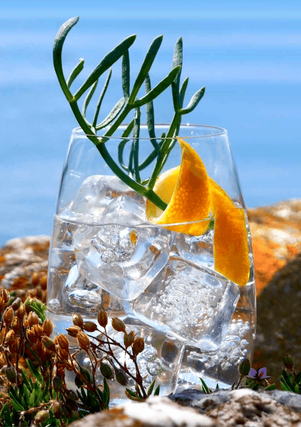 Gin and tonic mocktail garnished with fresh samphire and a lemon peel twist