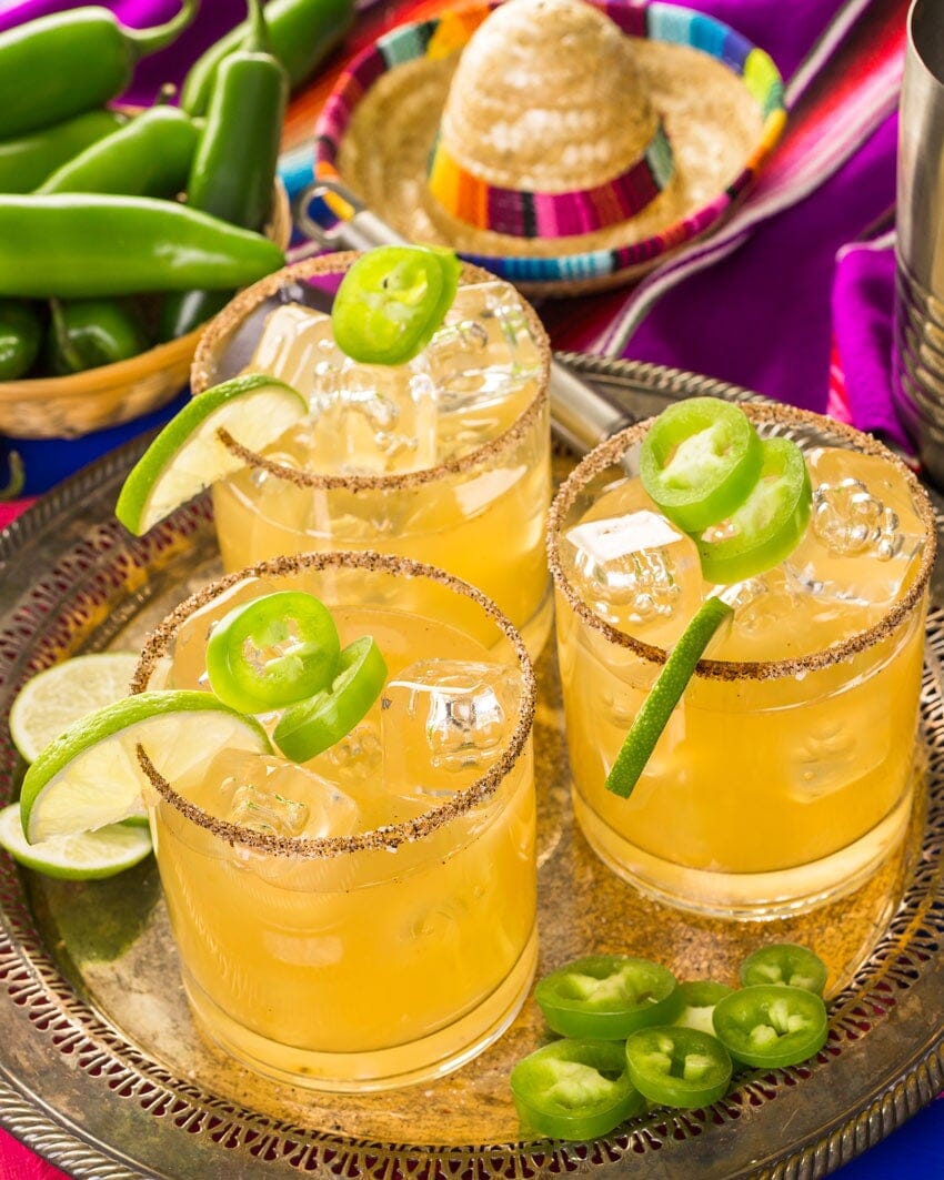 Three glasses of spicy margarita mocktails garnished with jalapeno slices and made with Ms Sans Margarita