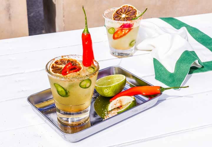 Chili Margarita Mocktail on a silver tray and garnished with red chilli and lime wheels