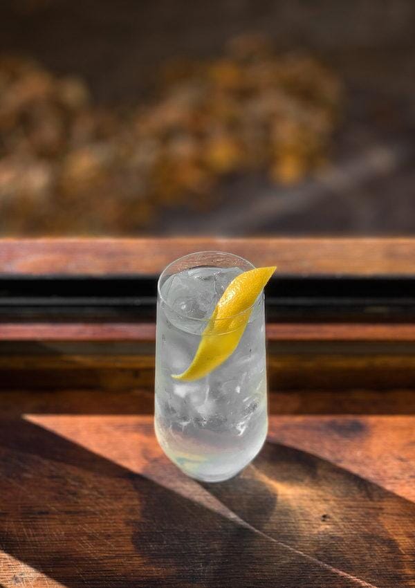 Elderflower gin mocktail in a tall glass garnished with lemon peel