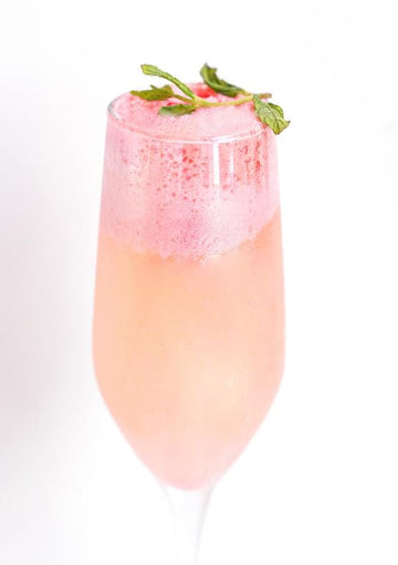 Champagne mocktail with raspberry sorbet and garnished with mint sprigs