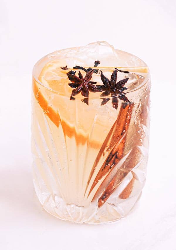 Cinnamon champagne mocktail garnished with star anise, a slice of orange and cinnamon sticks
