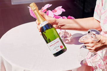 A woman holding a bottle of Barton & Guestier Alcohol-Free French Sparkling and two champagne glasses Sans Drinks