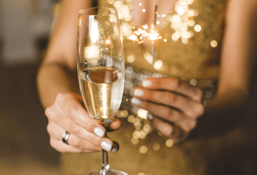 A woman holding a champagne glass and sparkle Sans Drinks