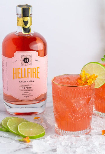 Non-alcoholic spritz garnished with lime wheel next to a bottle of Hellfire Inspirit