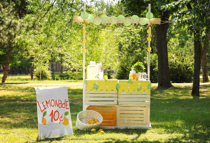 Lemonade stand at a park with a sign at the font which says lemonade 10 cents Sans Drinks