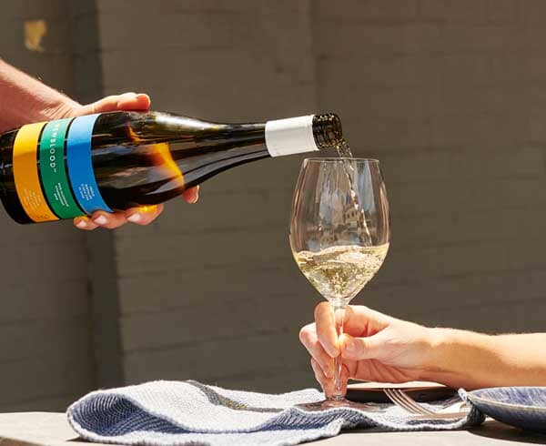 Person pouring a bottle of Newblood chardonnay into a glass