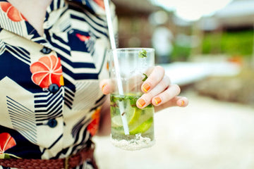 A woman holding a non-alcoholic rum mocktail Sans Drinks